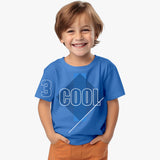 A smiling child wearing a blue short-sleeved cotton T-shirt with text and geometric patterns on it, standing against a white background.