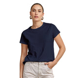 Woman wearing a navy blue t-shirt and light-colored pants on a white background