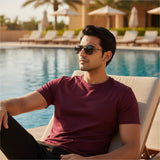 Man wearing sunglasses and a maroon shirt by a poolside
