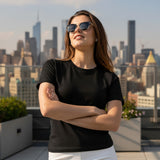 Woman wearing sunglasses and a black t-shirt with a city skyline in the background