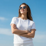 Woman wearing sunglasses and a white t-shirt against a clear blue sky